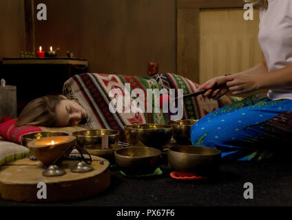 Femme avec des bols chantants tibétains. instructeur de yoga méditation mène le mouvement lent. Banque D'Images