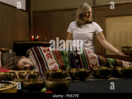 Femme avec des bols chantants tibétains. instructeur de yoga méditation mène le mouvement lent. Banque D'Images