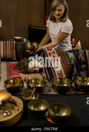 Femme avec des bols chantants tibétains. instructeur de yoga méditation mène le mouvement lent. Banque D'Images