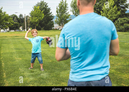 Un beau papa avec son petit mignon sun sont jouer au baseball sur pelouse verte Banque D'Images