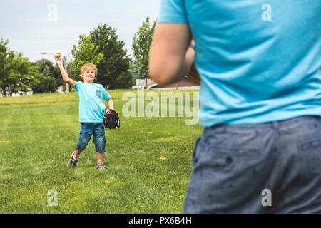 Un beau papa avec son petit mignon sun sont jouer au baseball sur pelouse verte Banque D'Images