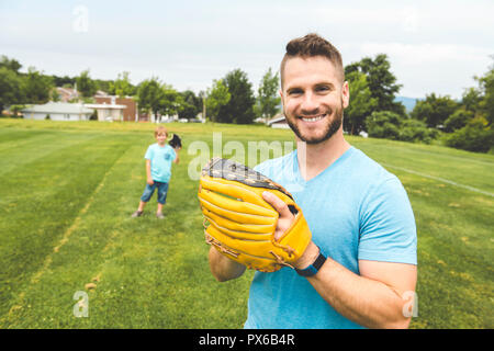 Un beau papa avec son petit mignon sun sont jouer au baseball sur pelouse verte Banque D'Images