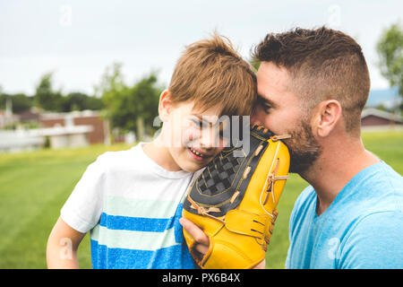 Un beau papa avec son petit mignon sun sont jouer au baseball sur pelouse verte Banque D'Images