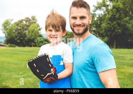 Un beau papa avec son petit mignon sun sont jouer au baseball sur pelouse verte Banque D'Images