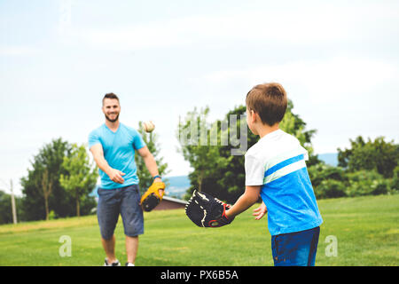 Un beau papa avec son petit mignon sun sont jouer au baseball sur pelouse verte Banque D'Images