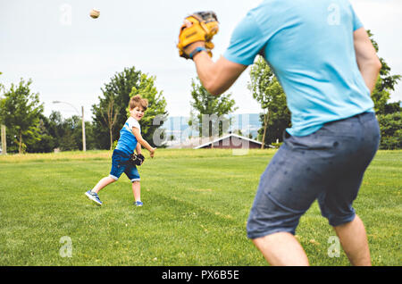 Un beau papa avec son petit mignon sun sont jouer au baseball sur pelouse verte Banque D'Images