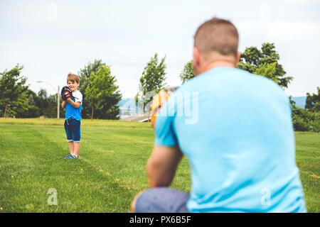 Un beau papa avec son petit mignon sun sont jouer au baseball sur pelouse verte Banque D'Images