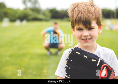 Un beau papa avec son petit mignon sun sont jouer au baseball sur pelouse verte Banque D'Images