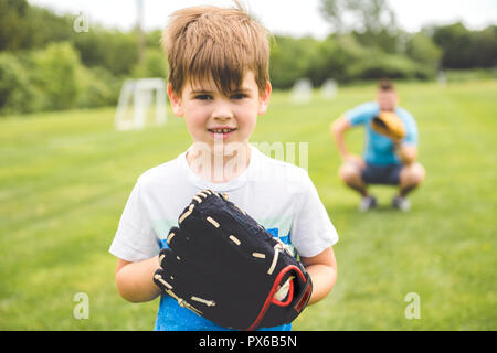 Un beau papa avec son petit mignon sun sont jouer au baseball sur pelouse verte Banque D'Images