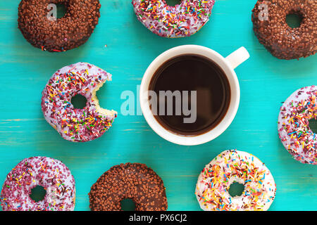 De délicieux beignets glacés et tasse de café sur la surface turquoise. Mise à plat des aliments minimaliste art fond. Vue d'en haut. Banque D'Images