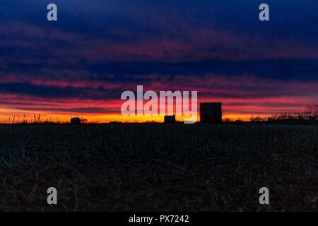 Champ avec de l'herbe sèche tondu sur l'arrière-plan d'un incroyable coucher du soleil. L'herbe est recueilli dans les meules. Banque D'Images