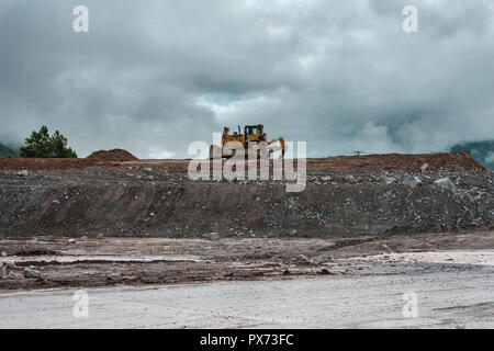 Bulldozer jaune prend une pause sur la rive du fleuve Banque D'Images