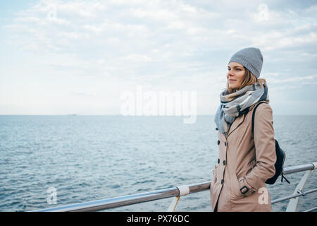 Happy young woman on quai de la mer à la route. Femme debout sur fond bleu d'eau en hiver smiling bénéficiant d'afficher, copier l'espace. Banque D'Images