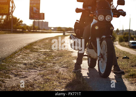 Vue rapprochée sur le motard assis sur la moto sur une route vide de Banque D'Images