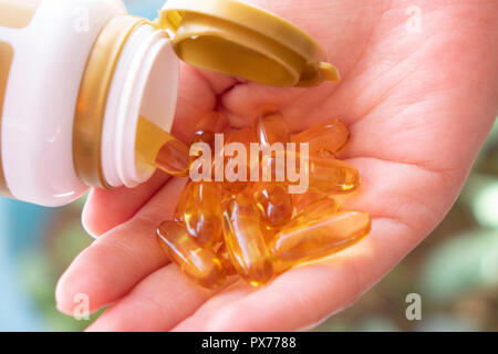 Le sport, mode de vie sain, des médicaments, des suppléments nutritionnels et des personnes concept - close up of man avec verre de l'eau verser des capsules d'huile de poisson de ja Banque D'Images