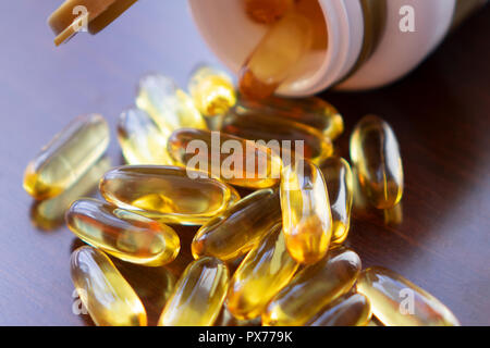 Des capsules d'huile de poisson à l'oméga 3 et de vitamine D dans une bouteille en verre sur la texture en bois, alimentation saine notion,close up shot. Banque D'Images
