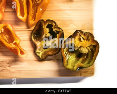 Shot de Naga orange Moric poivrons sur une planche à découper, en tranches avec un couteau Banque D'Images