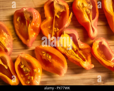 Shot de Naga orange Moric poivrons sur une planche à découper, en tranches avec un couteau Banque D'Images