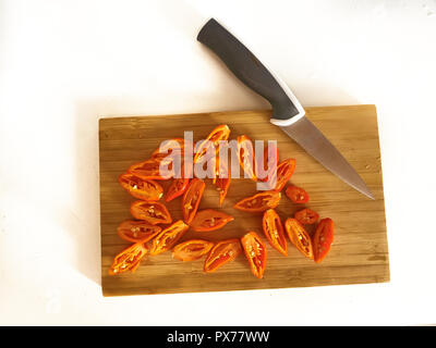 Shot de Naga Morich orange poivrons sur une planche à découper, en tranches avec un couteau Banque D'Images