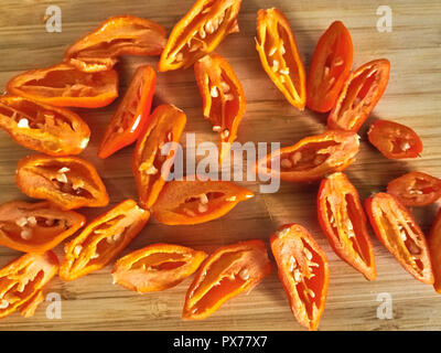 Shot de Naga Morich orange poivrons sur une planche à découper Banque D'Images