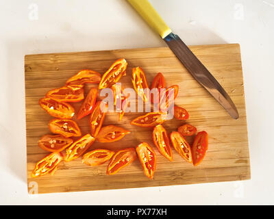 Shot de Naga Morich orange poivrons sur une planche à découper, en tranches avec un couteau Banque D'Images