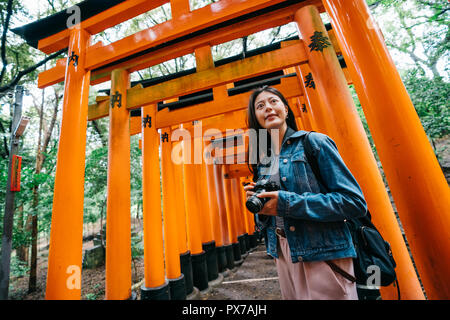 Photographe asiatique photo de la porte rouge japonaise par son appareil photo reflex numérique. Dame lens homme voyageant à Kyoto au Japon. Le texte porte sur la traduction ' Banque D'Images