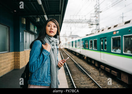 Femme élégante traveler debout sur la gare et le train venant d'attente. Gare trajet du matin femme de se rendre au travail. Les gens sur les tran Banque D'Images