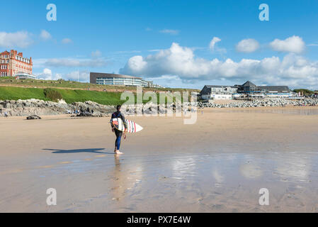 Un surfer carrying surfboard sa marche sur la plage de Fistral à Newquay en Cornouailles. Banque D'Images