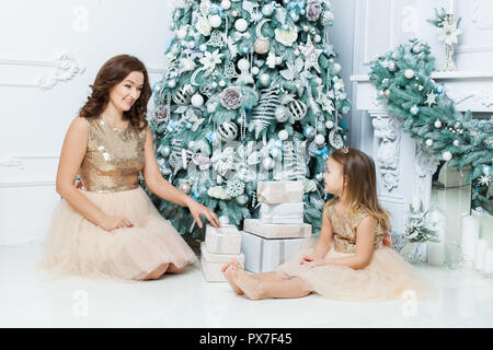 Maman et sa fille assis sous l'arbre de Noël près de la boîtes à cadeaux. Banque D'Images