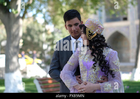 Un marié ouzbek pose avec une mariée portant une casquette traditionnelle en tubeteika lors d'une séance de photographie pré mariage dans la vieille ville de Boukhara en Ouzbékistan Banque D'Images
