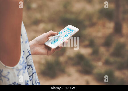 La lecture d'une image sur un écran de téléphone concept. Close up on a woman's hand holding a smart phone, affichage d'informations Banque D'Images