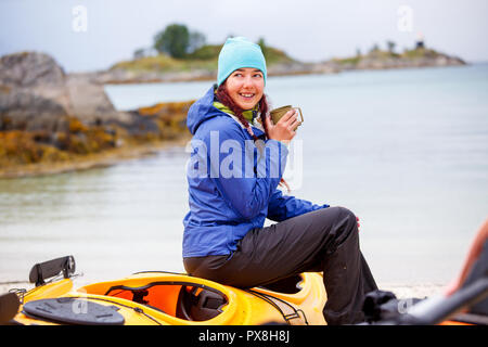 Photo de happy female tourist avec tasse assis sur kayak sur rivière, Banque D'Images