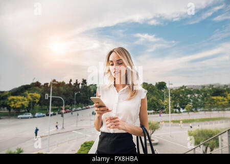 Belle jeune femme d'affaires de l'exécutif est l'utilisation d'une application dans son smart phone pour vérifier vos e-mails ou envoyer un message texte Banque D'Images