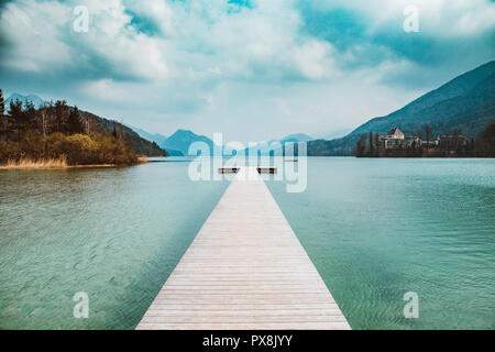 Panorama pittoresque vue d'un ponton en bois idyllique sur un magnifique lac dans les Alpes sur un jour nuageux moody en été Banque D'Images