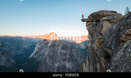 L'intrépide randonneur est debout sur un rocher en surplomb en profitant de la vue vers célèbre Demi Dôme à Glacier Point oublier dans beau crépuscule du soir