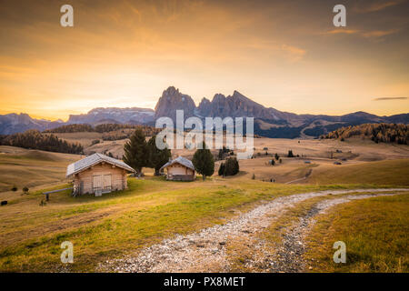 Belle vue sur la montagne chalets traditionnels en bois sur Scenic Alpe di Siusi célèbre Langkofel avec des pics de montagne dans l'arrière-plan dans la matinée d'or Banque D'Images