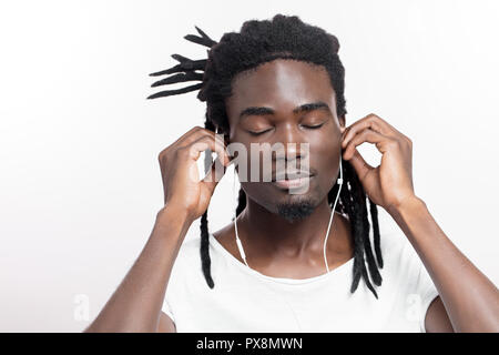 Homme teint foncé avec des dreadlocks à l'écoute de la musique sur le casque Banque D'Images