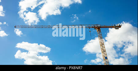 En construction. Grue à tour jaune sur fond de ciel bleu Banque D'Images