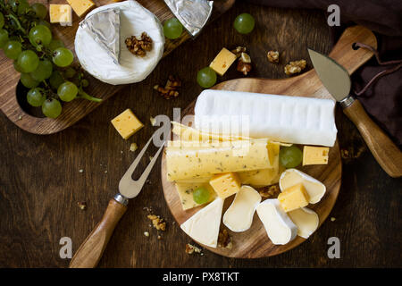 Assiette de fromage. Assortiment de fromages, les raisins et les noix sur la table rustique en bois sombre. Vue supérieure de la télévision mise de fond. Banque D'Images