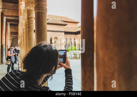 Fontaine des Lions, la célèbre fontaine de marbre maure de Grenade Espagne cour intérieure. Jeune fille de tourisme de prendre une photo Banque D'Images