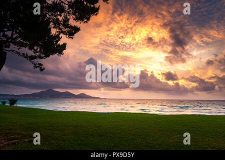 Majorque Puerto de Alcudia beach au lever du soleil dans la baie d'Alcudia à Majorque Îles Baléares de l'Espagne. Soleil se lève près de la montagne dans la mer. Banque D'Images