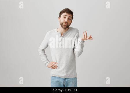 Homme de race blanche désagréable snob avec barbe, expliquant quelque chose tout en gesticulant avec les mains, faire comme si il sait tout, debout sur fond gris. Les possibilités d'un poids jusqu'Comités Banque D'Images