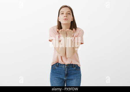 Bisous à chaud fille envoie des disciples. L'insouciante élégant femme en t-shirt rose, se pencher vers la caméra, holding palms près de lèvres pliées en donnant mwah, exprimer l'amour et les émotions d'offres Banque D'Images