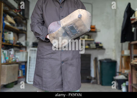 Soudeur dans un atelier de mécanique. Un employé tout en travaillant sur le lieu de travail. Un serrurier atelier dans l'arrière-plan. Banque D'Images