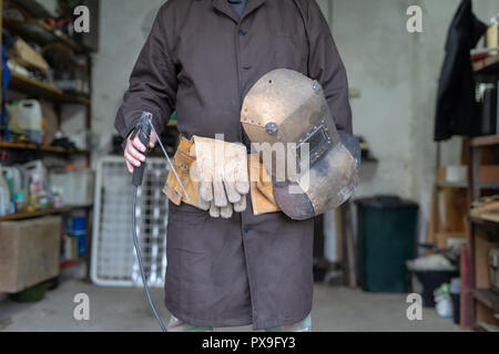 Soudeur dans un atelier de mécanique. Un employé tout en travaillant sur le lieu de travail. Un serrurier atelier dans l'arrière-plan. Banque D'Images