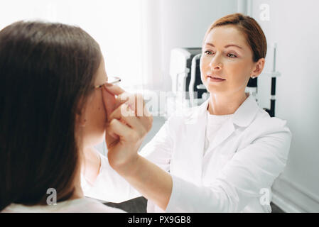 Optomerist est de mettre de nouvelles lunettes sur le visage de fille Banque D'Images