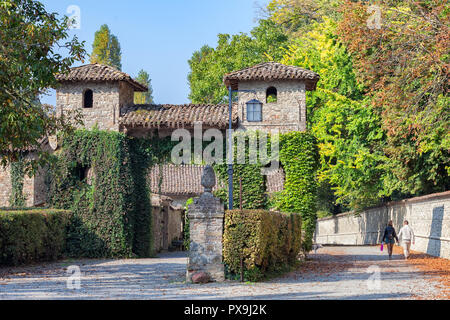 Jeune couple en train de marcher au milieu d'un chemin d'automne vers le château de Grazzano Visconti, Piacenza, Italie Banque D'Images