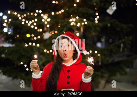 Maison de vacances de Noël, et les gens heureux jeune concept - costume woman holding bengale lumière sur fond d'arbre de Noël Banque D'Images