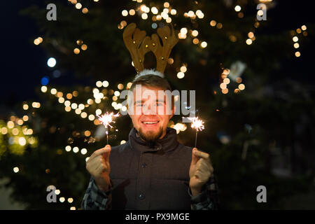 Les gens, les vacances de Noël - concept et surpris l'homme dans les cornes de cerf tenant deux baguettes à la lumière ou à l'extérieur des bengals Banque D'Images