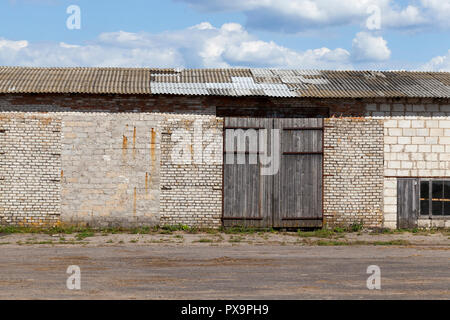 Ancien entrepôt de brique avec de grandes portes fermées, ciel bleu Banque D'Images